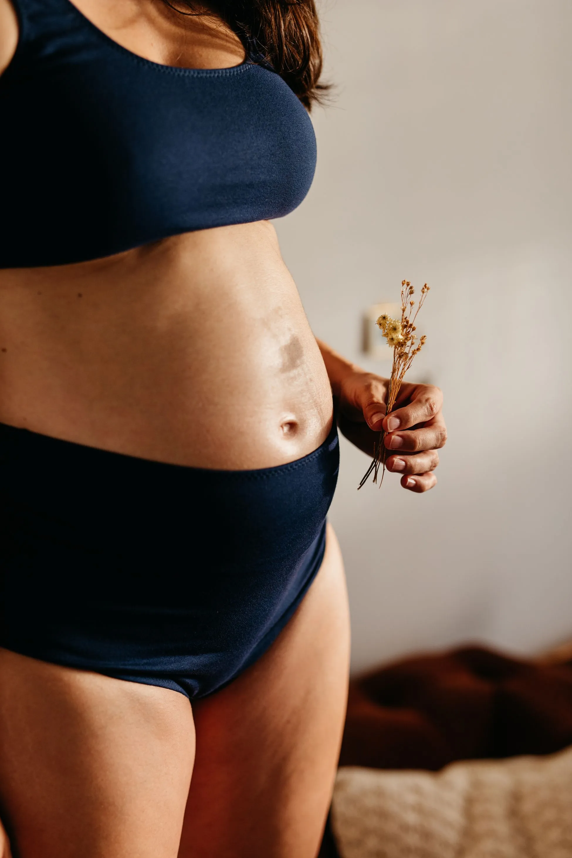 A pregnant woman holding dried flowers.